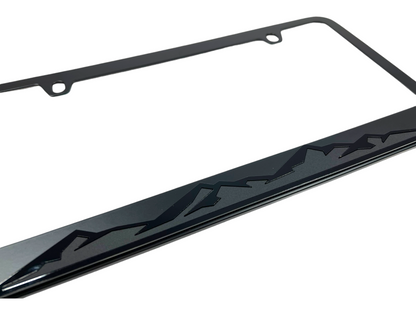 a black license plate frame with mountains on it